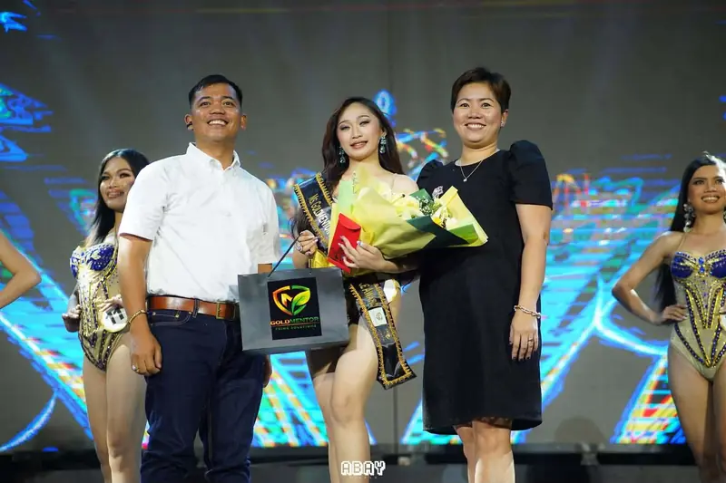 Our team handing a Goldmentor gift bag and flowers to a pageant winner on stage